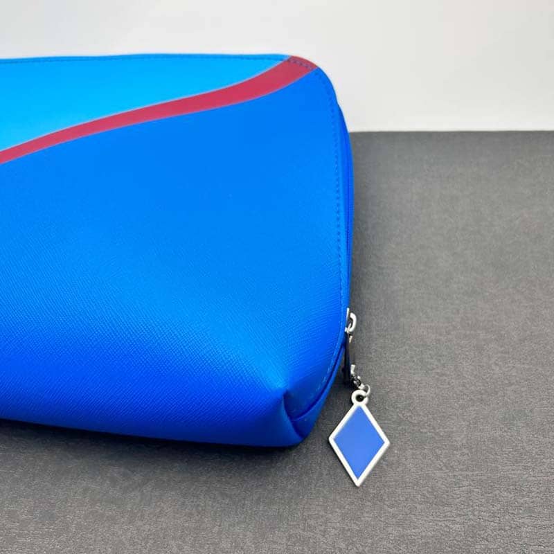 A blue pouch with a red diagonal stripe across the top, perfect for custom merchandise or promotional products. It features a silver zipper adorned with a diamond-shaped blue and silver charm, and rests on a gray surface.